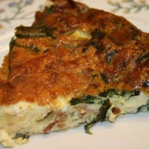 A closeup of a slice of Spinach and Bacon crustless quiche on a plate