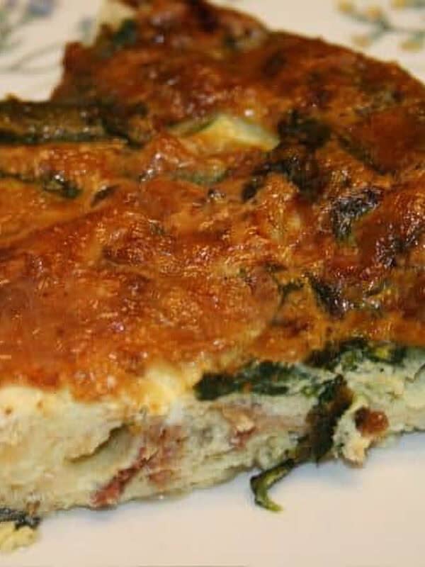 A closeup of a slice of Spinach and Bacon crustless quiche on a plate