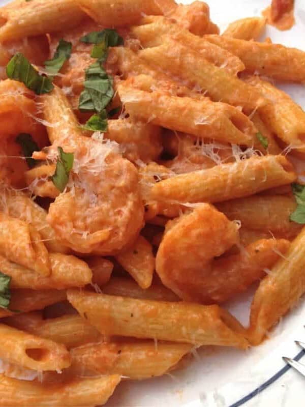 An overhead view of Shrimp and Penne Pasta with Creamy Marinara Sauce topped with grated parmesan cheese on a plate with a fork