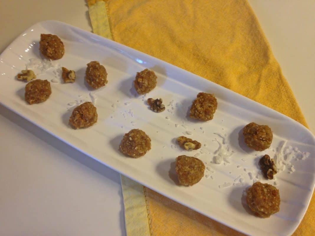 Ten Fruity Nut Balls with scattered shredded coconut and chopped walnuts on a rectangle serving dish on a yellow cloth napkin 