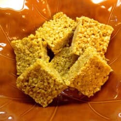 An overhead view of Six Pumpkin Spice Rice Krispies Treats in a large leaf-shaped serving bowl