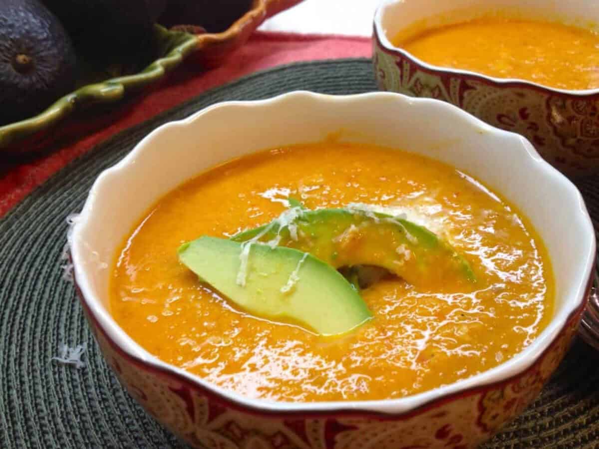 Roasted Corn and Tomato Soup from Zagleft A bowl of Roasted Sweet Corn and Tomato Soup topped with two slices of avocado and grated asiago cheese next to another bowl of soup