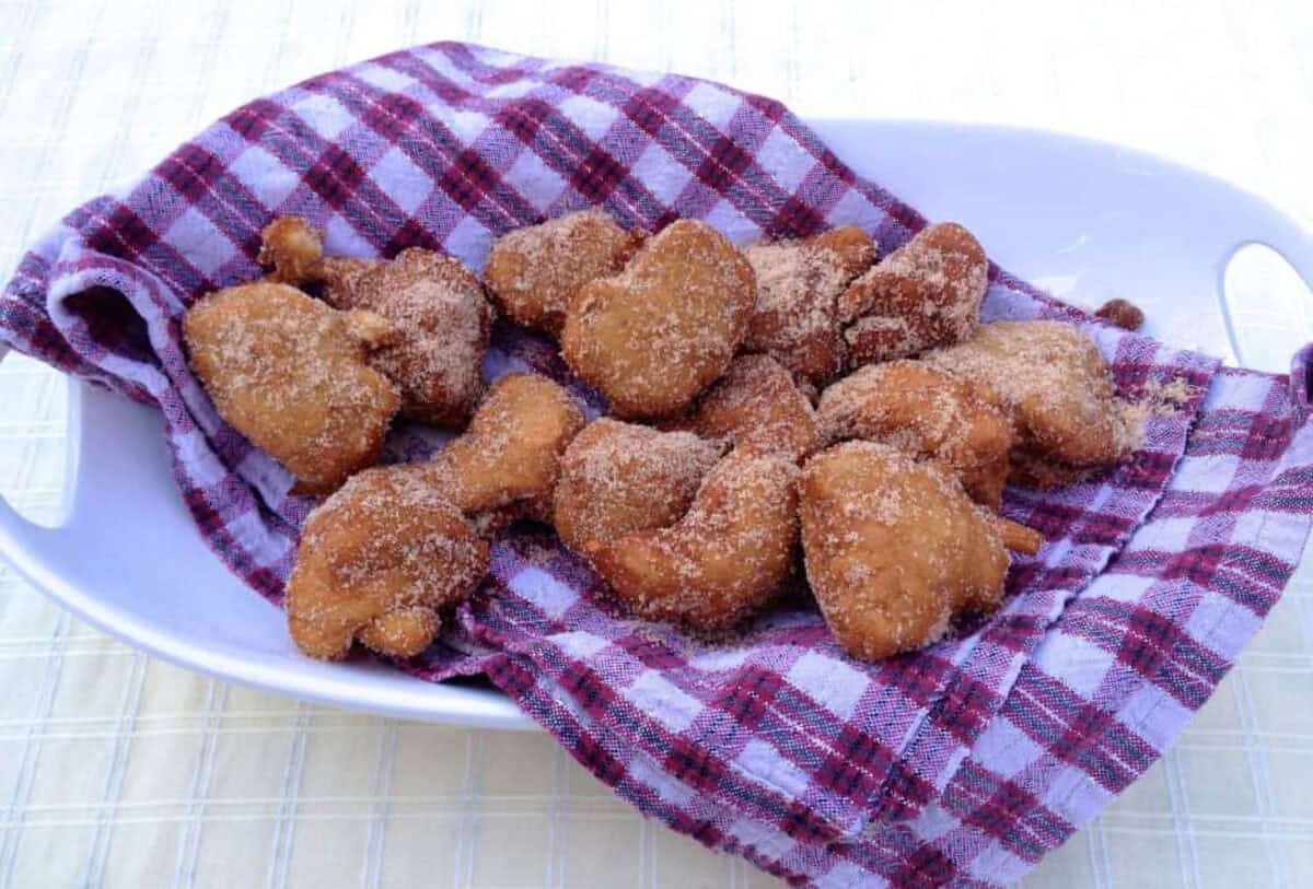 Banana Beignets from Zagleft Banana Beignets coated in cinnamon sugar on top of a red and white checkered cloth napkin in an oval-shaped dish
