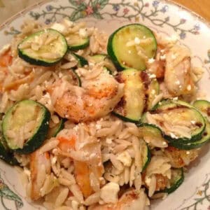 An overhead view of Greek Shrimp with Zucchini and Orzo and topped with Feta cheese crumbles in a bowl