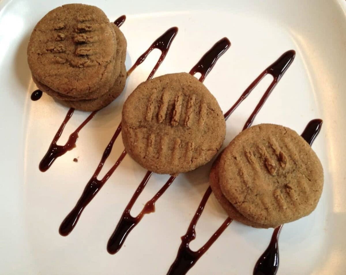 Honey Molasses Cookies From Zagleft -2 An overhead view of three stacks of Honey Molasses Cookies on a square plate that is drizzled with chocolate syrup
