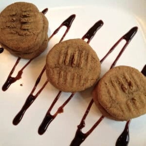 An overhead view of three stacks of Honey Molasses Cookies on a square plate that is drizzled with chocolate syrup