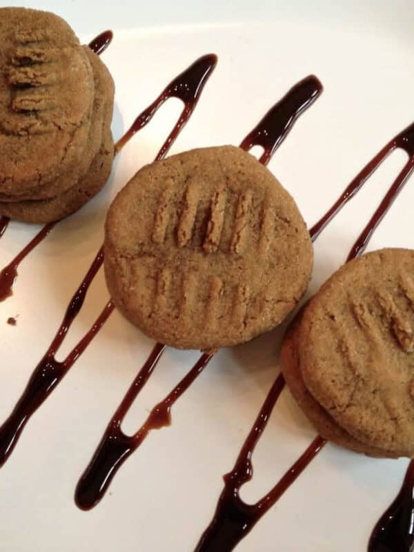 An overhead view of three stacks of Honey Molasses Cookies on a square plate that is drizzled with chocolate syrup