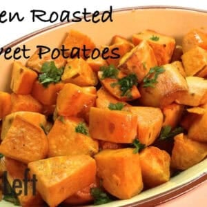 A baking dish of chopped oven roasted sweet potatoes topped with chopped parsley