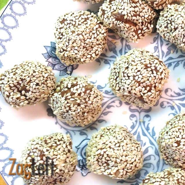 A closeup of ten Almond Butter Energy Bites coated with sesame seeds on a plate
