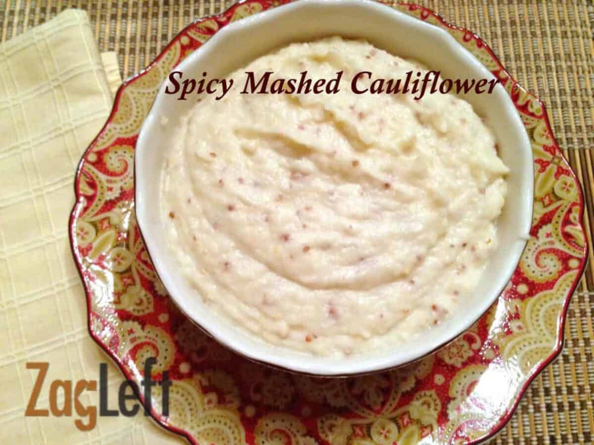 Overhead view of a bowl of Spicy Mashed Cauliflower plated next to a yellow cloth napkin