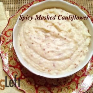 Overhead view of a bowl of Spicy Mashed Cauliflower plated next to a yellow cloth napkin