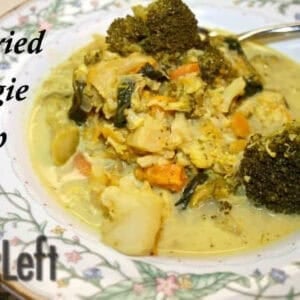 A bowl of Curried Veggie Soup with thick pieces of cauliflower, broccoli, carrots, sweet potatoes, spinach and sweet apples.
