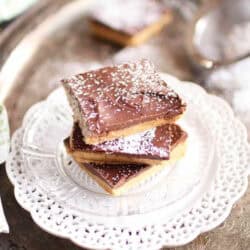 A stack of three No Bake Chocolate Peanut Butter Bars dusted with powdered sugar on a small plate on a metal tray