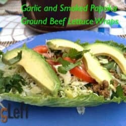 Ground beef lettuce wrap topped with shredded lettuce, three avocado slices, two tomato slices, and cilantro on a large plate