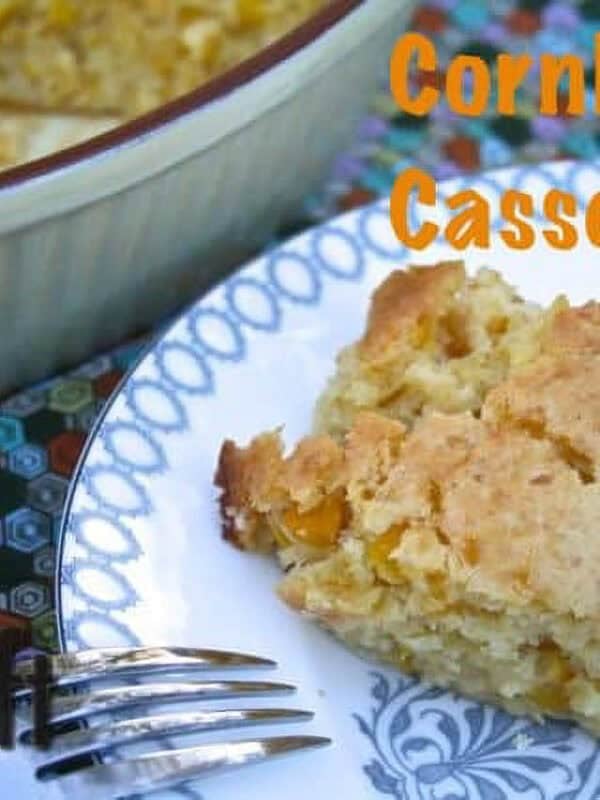 A square slice of Cornbread Casserole on a plate next to the remainder of the casserole in a serving dish