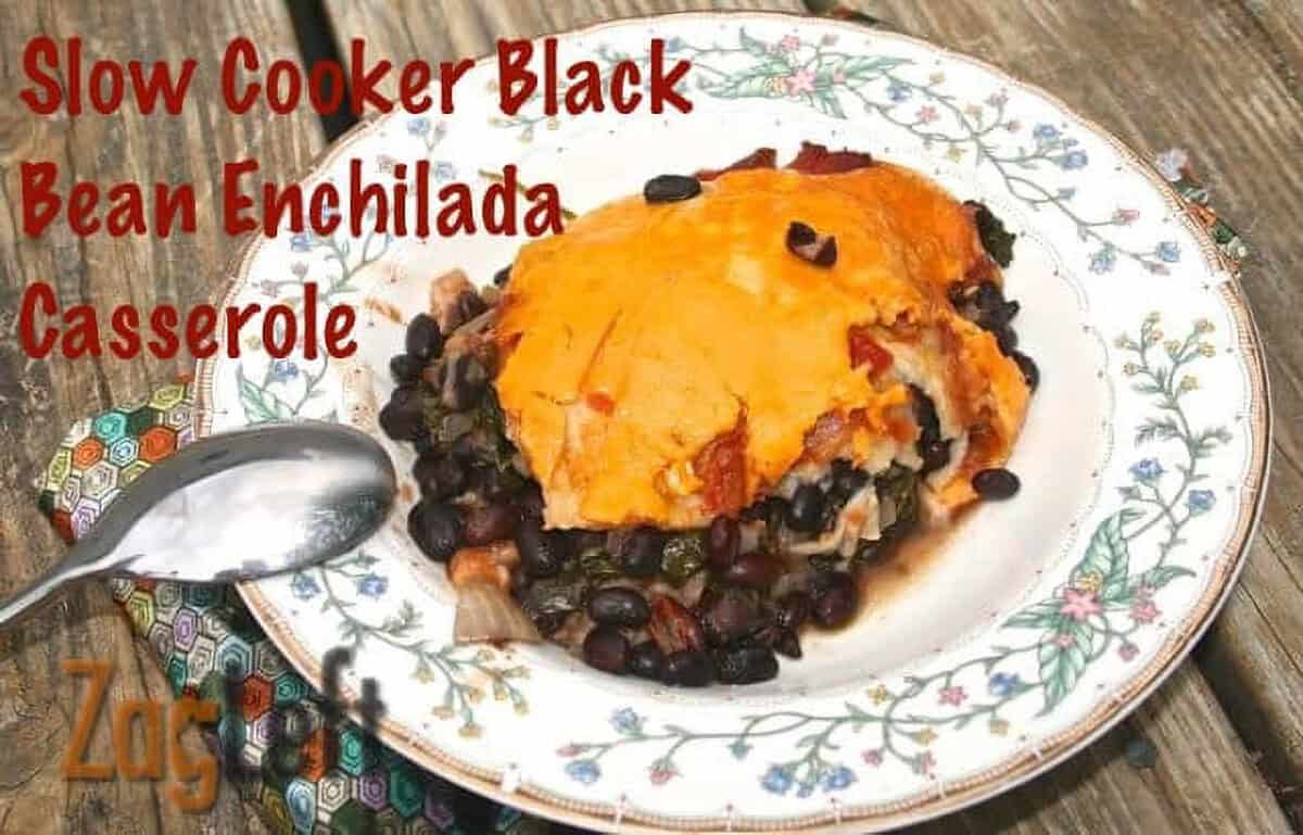 A bowl of Slow Cooker Black Bean Enchilada Casserole topped with a layer of melted cheese with a spoon resting on the side of the bowl