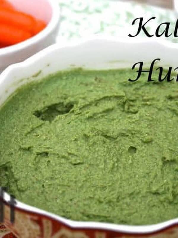 A bowl of Kale Hummus plated next to a small bowl of baby carrots