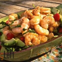 Avocado Salad with cherry tomatoes topped with grilled shrimp in a long green serving dish on a wooden surface
