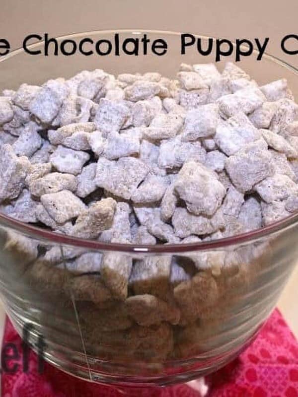 Blue and white sugar-coated puppy chow snack in glass bowl, perfect for sharing on food and travel blogs.