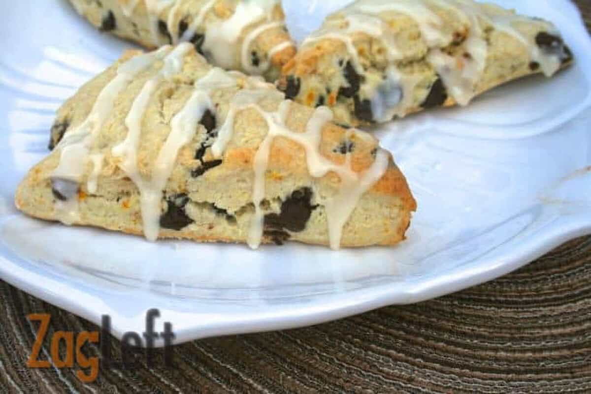 Three Dark Chocolate Orange Scones drizzled with white icing on a large plate