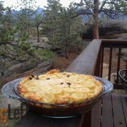 A Banana and Chocolate Puffed Pastry in a glass pie dish with a forest in the background