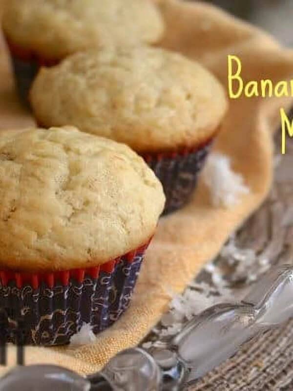 Six Banana Coconut Muffins on a large glass plate with coconut shavings