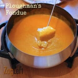 Dipping a piece of french bread into a fondue pot of Ploughman's Fondue