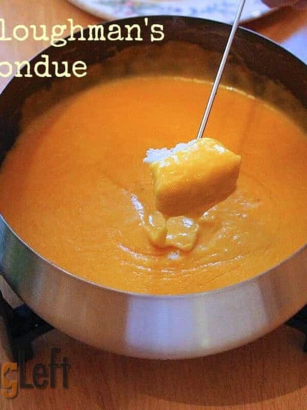 Dipping a piece of french bread into a fondue pot of Ploughman's Fondue