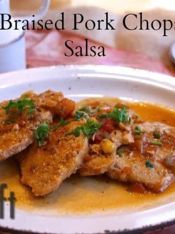 Four Quick Braised Pork Chops topped With Salsa on an oval shaped plate next to a half stick of butter on a small plate