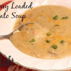 A bowl of Creamy Loaded Potato Soup with a spoon topped with shredded cheese