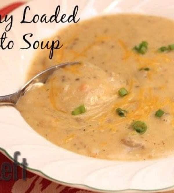 A bowl of Creamy Loaded Potato Soup with a spoon topped with shredded cheese