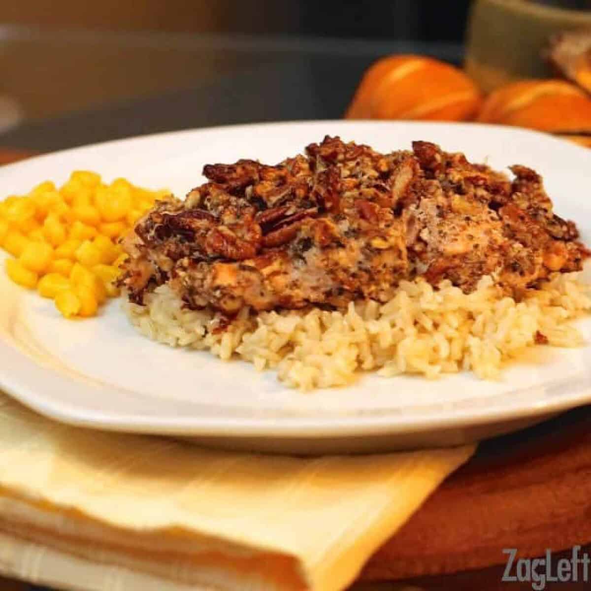 Parmesan Pecan Crusted Salmon on a bed of rice next to a side of corn on a large plate