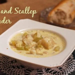 A bowl of Fish and Scallop Chowder on a doily next to a slice of french bread on a small plate