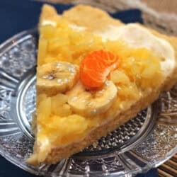 A slice of Pineapple Shortbread Pizza topped with two banana slices and a slice of Mandarin orange on a small plate