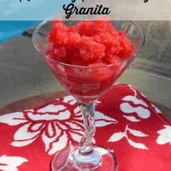 Sparkling Strawberry Granita in a tall dessert glass on a red cloth napkin with a pool in the background