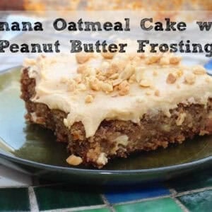 A slice of Banana Oatmeal Sheet Cake topped with Creamy Peanut Butter Frosting and chopped peanuts on a small plate next to the remainder of the cake in a baking dish on a cooling rack and a glass of milk and a fork