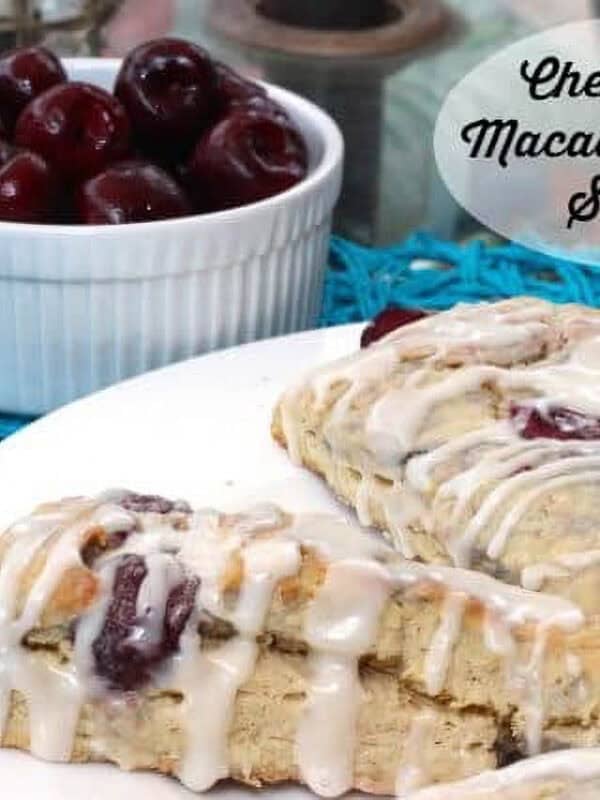 Cherry and Macadamia nut scone drizzled with frosting and sitting on a white dish.