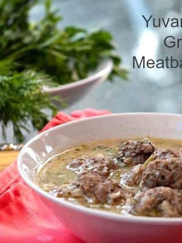A bowl of Yuvarlakia - Greek Meatball Soup next to a bowl of dill and parsley.