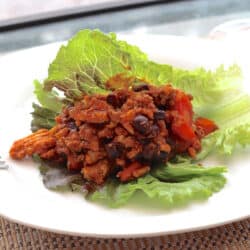 sloppy joe with meat and tomatoes sitting on a bed of lettuce.