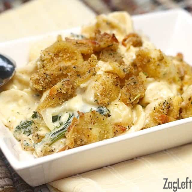A closeup of a square plate of Macaroni and Cheese with Kale and Gruyere topped with breadcrumbs
