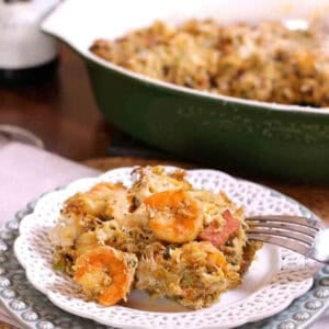 Seafood Stuffed Eggplant Casserole on a small plate with the remainder of the casserole in a baking dish in the background
