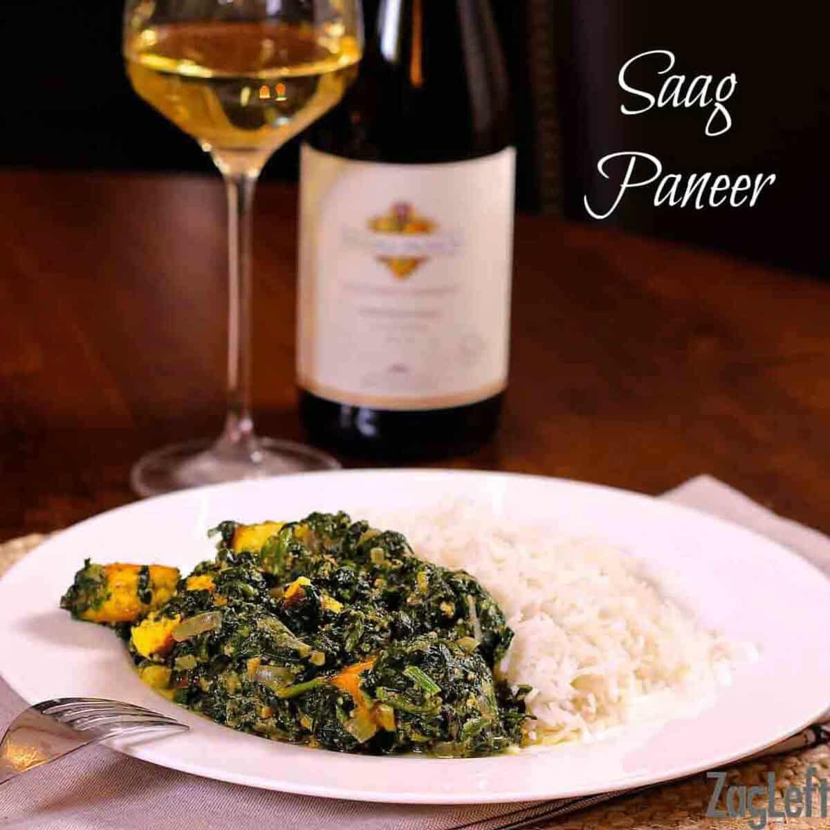Saag Paneer and basmati rice on a large plate next to a glass and bottle of white wine