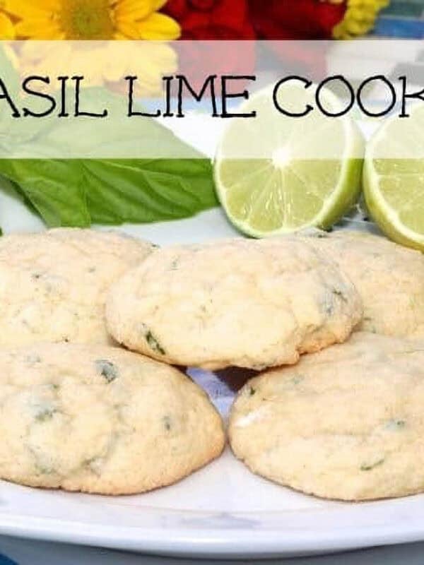 Five Basil Lime Cookies on a large plate with two lime halves and two large basil leaves