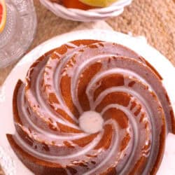 An overhead view of Lemon Grapefruit Buttermilk Cake topped with white icing next to a large bowl of grapefruits and oranges