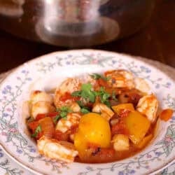 A bowl of Spicy Shrimp and Scallops next to a large pot with the remainder of the dish