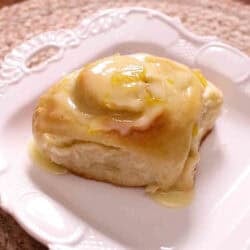 A Pineapple Sweet Roll topped with a glaze on a small plate