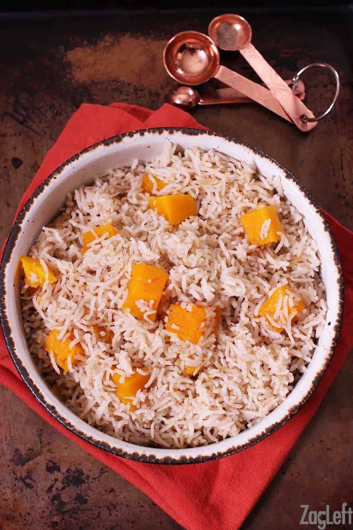 Spiced Butternut Squash Basmati Rice in a large bowl on top of a red cloth napkin and next to measuring spoons