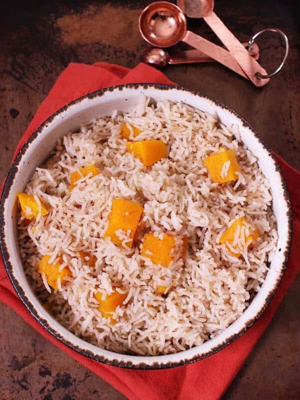 Spiced Butternut Squash Basmati Rice in a large bowl on top of a red cloth napkin and next to measuring spoons