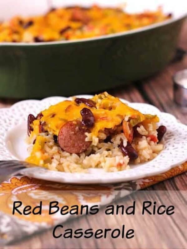 A plate of Red Beans and Rice Casserole topped with melted cheese with a casserole dish in the background