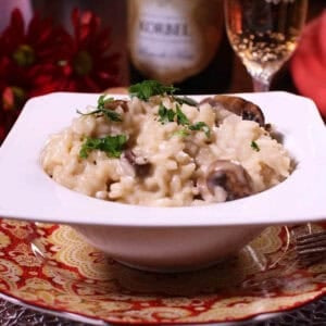 Champagne Risotto in a bowl plated next to a bottle and a flute of champagne